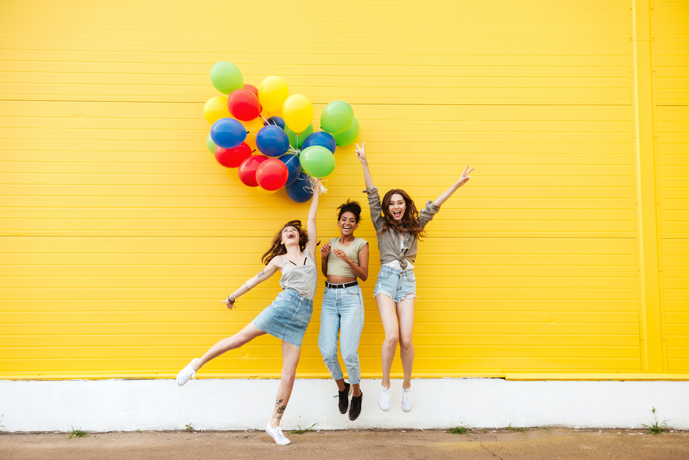 Girlfriends having fun in front of a yellow wall